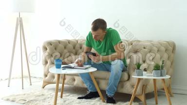严肃的男人坐在沙发上用数码平板电脑写日记